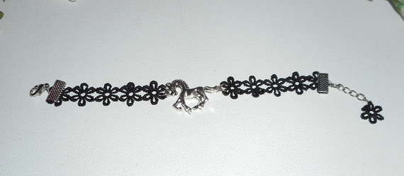 Bracelete original com cavalo de metal prateado sobre renda preta