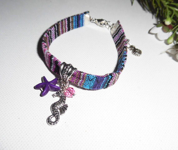 Pulseira de tecido colorido com cavalo marinho e borlas de estrela-do-mar roxas