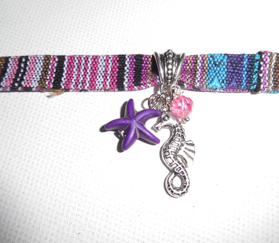 Pulseira de tecido colorido com cavalo marinho e borlas de estrela-do-mar roxas