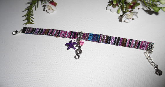 Pulseira de tecido colorido com cavalo marinho e borlas de estrela-do-mar roxas