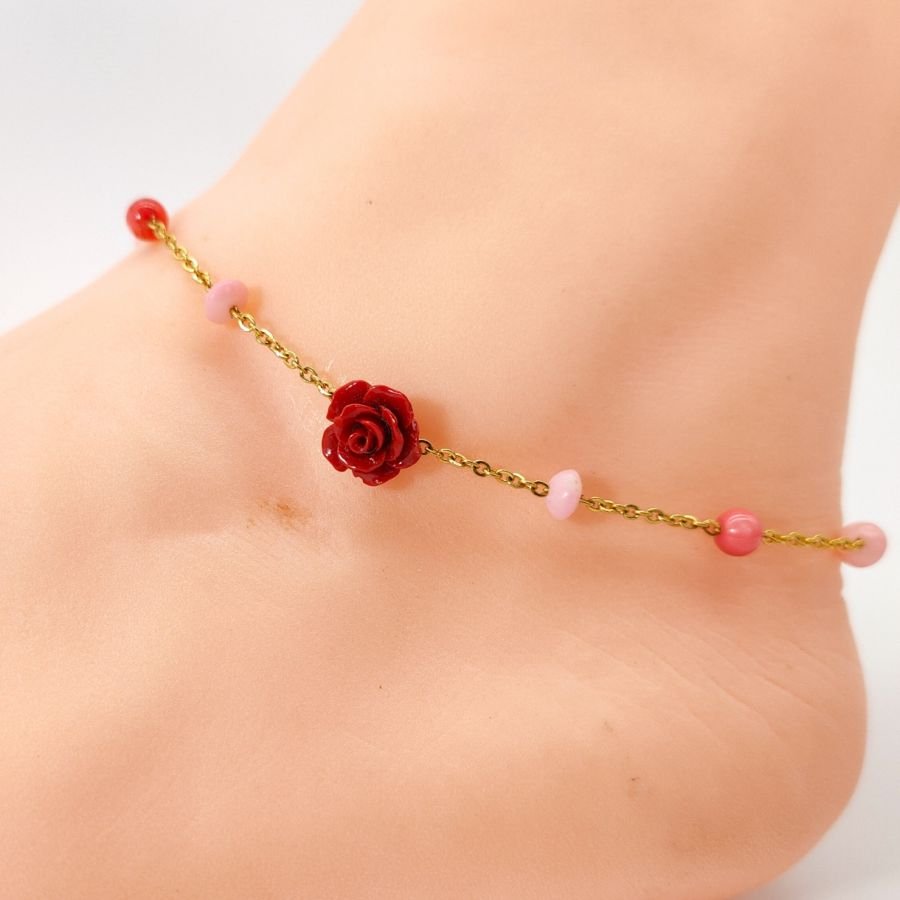 Tornozeleira de coral com rosa vermelha sobre corrente de aço dourada